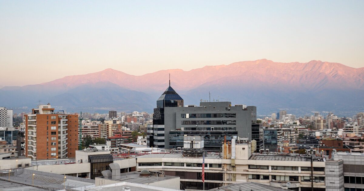 A city skyline with a mountain range rising behind it at dusk